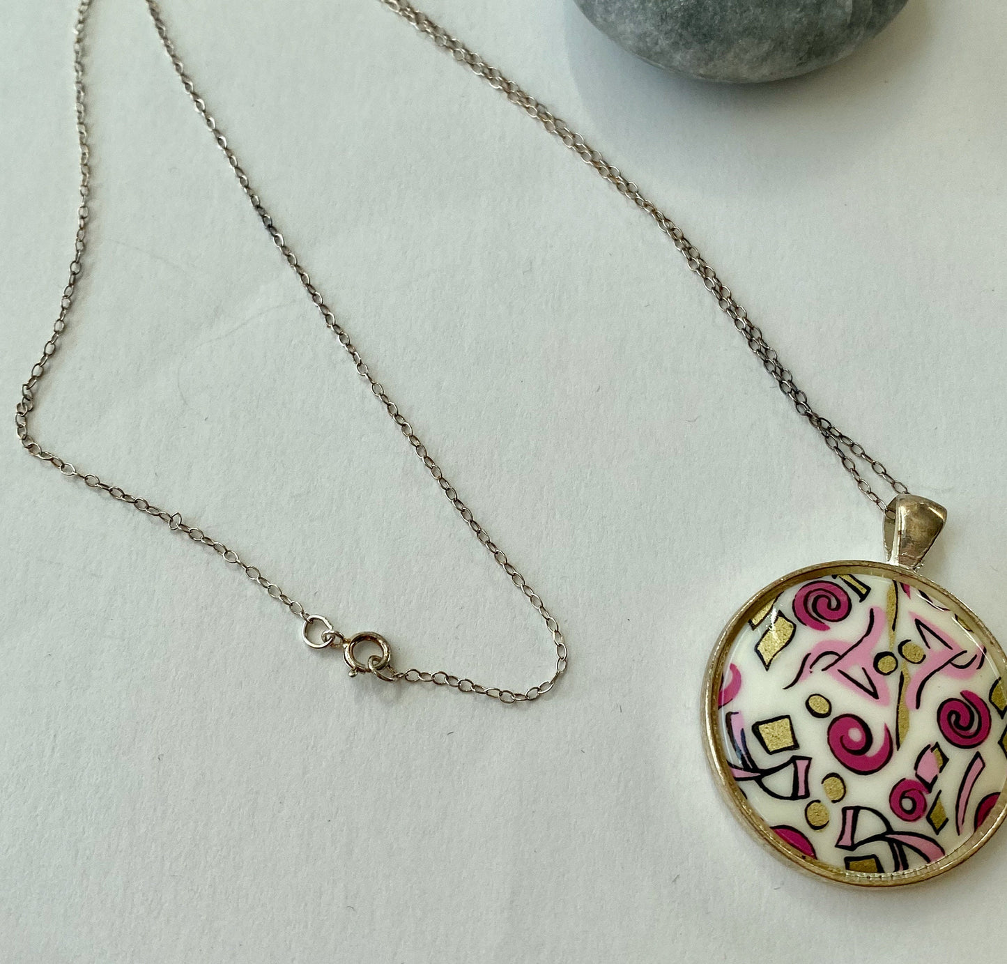 Beautiful retro look pendant.  Set in a silver bezel on a sterling silver chain. Pink and gold fun design.