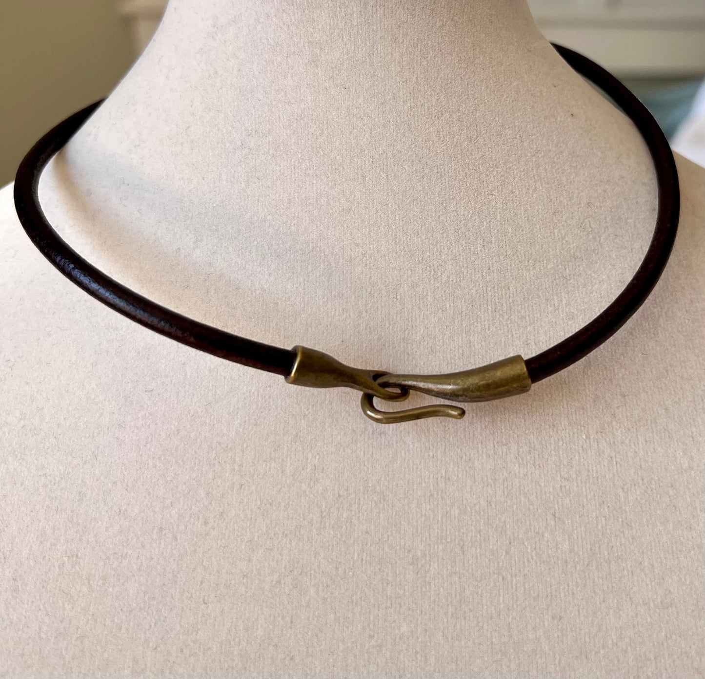 Leather Necklace  Dark brown leather necklace with bronze hook and eye. Front clasp for focus. 16.5" long.