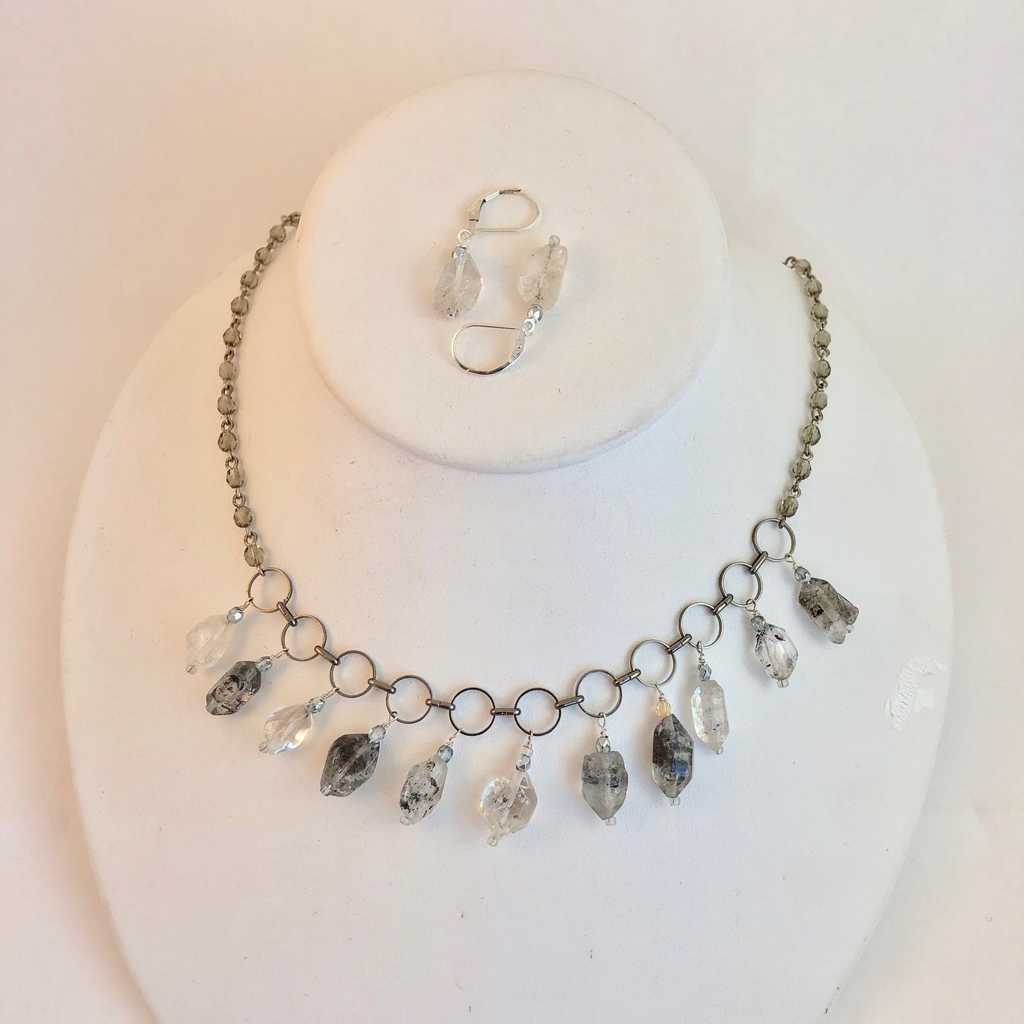 Necklace of crystal quartz gemstone, which offer strength.  Stones hang from metal circles, stung on a chain with glass embedded stones.