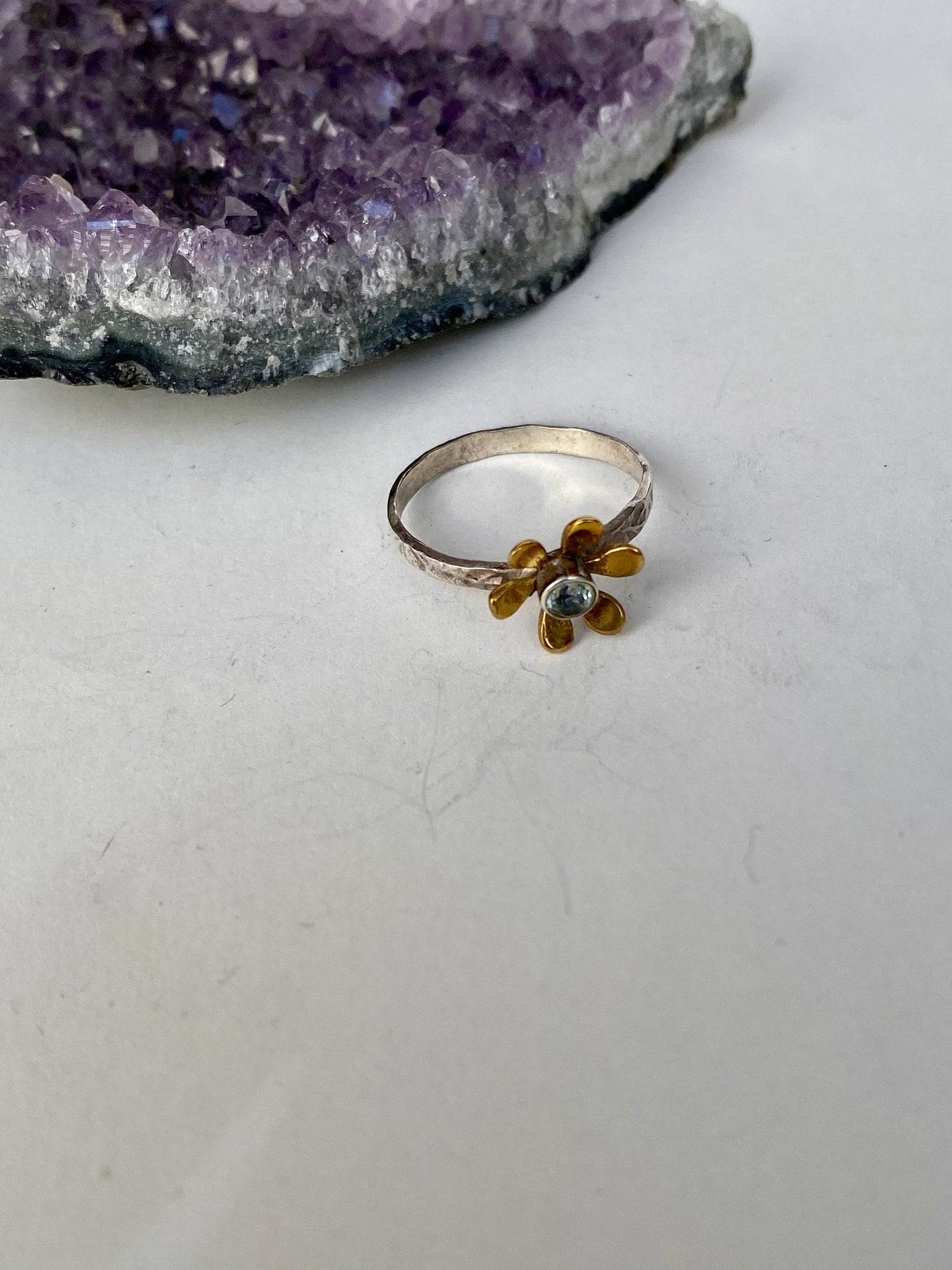 Precious size 7 ring with sterling silver band, blue topaz and brass flower design.