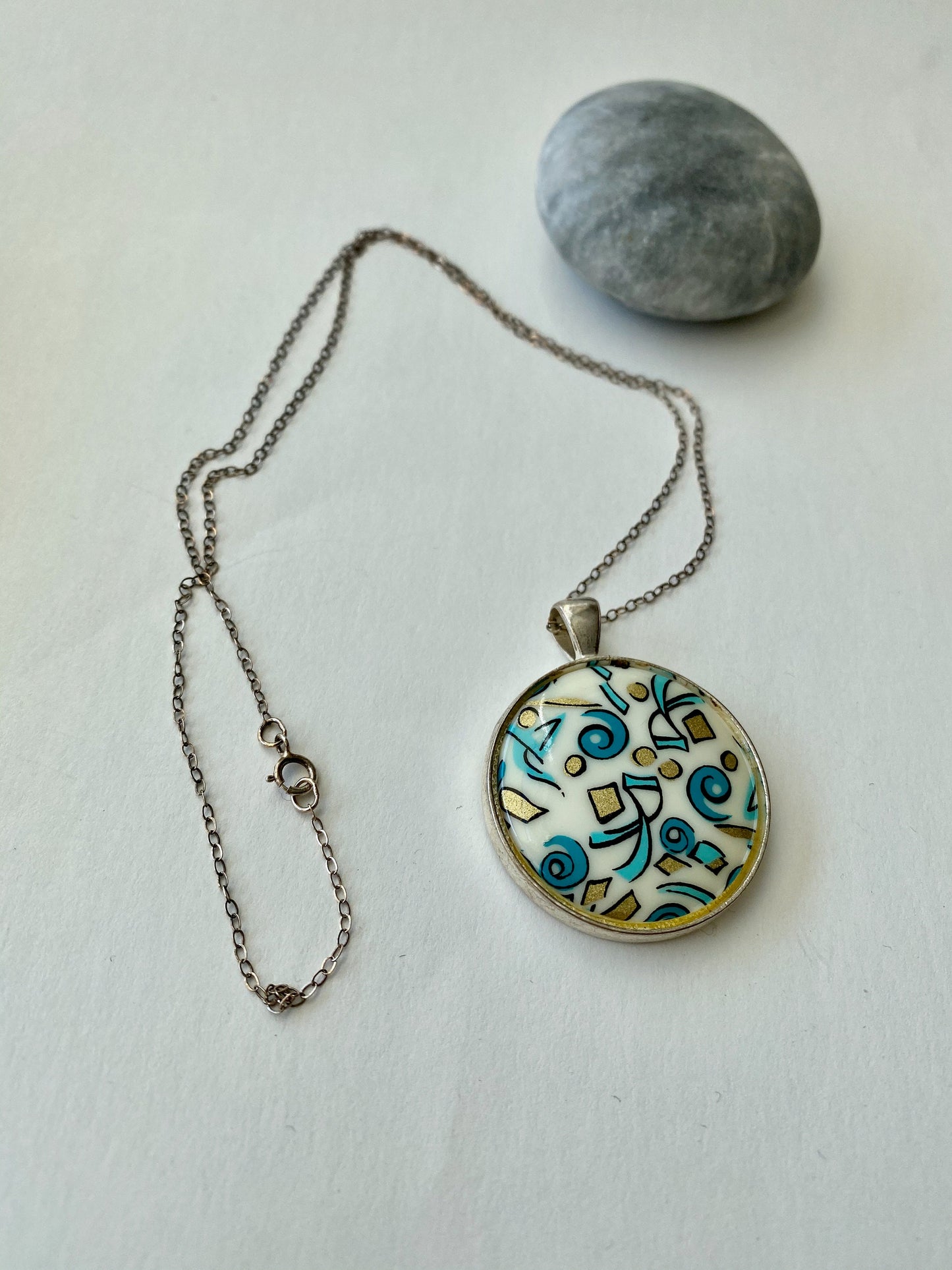 Beautiful retro look pendant.  Set in a silver bezel on a sterling silver chain. Blue and gold fun design.