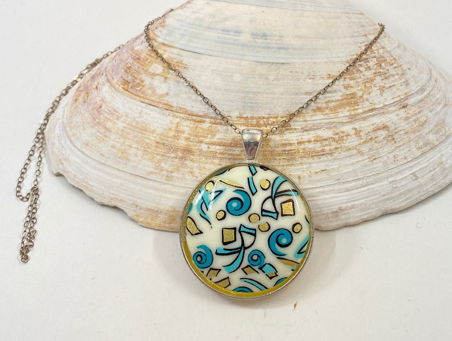 Beautiful retro look pendant.  Set in a silver bezel on a sterling silver chain. Blue and gold fun design.