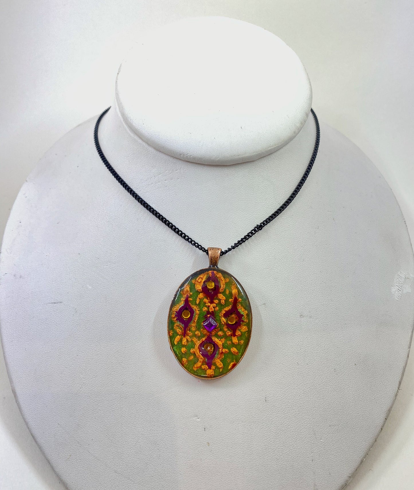 Glass and crystal pendant. Hand painted design accented with crystal beads. Silver frame and 28" contrasting black chain.