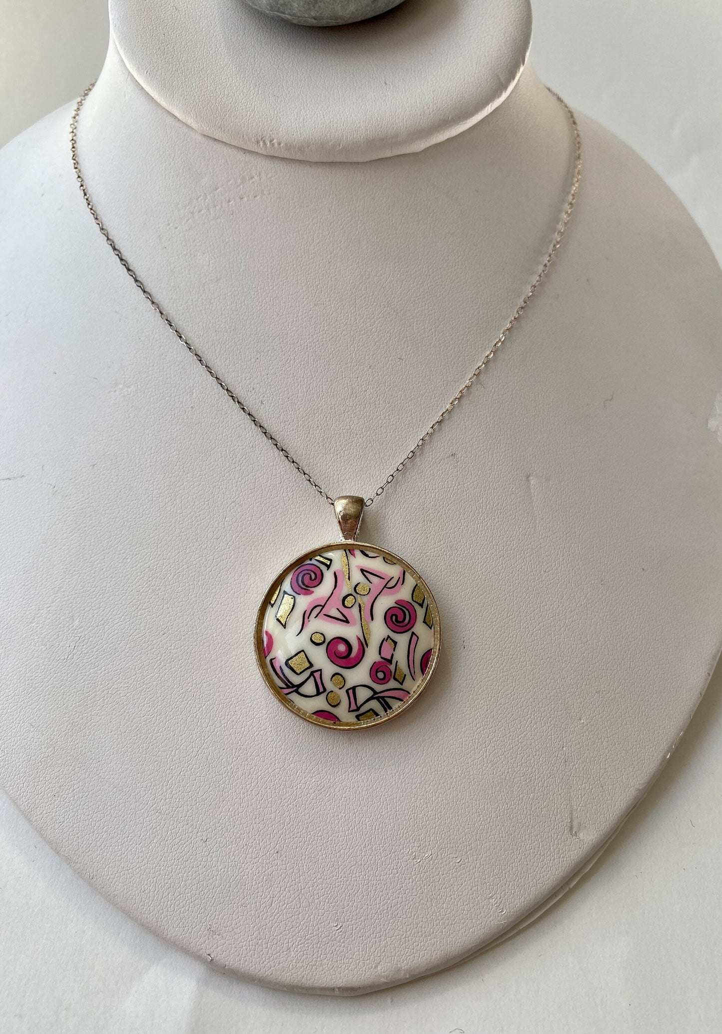 Beautiful retro look pendant.  Set in a silver bezel on a sterling silver chain. Pink and gold fun design.