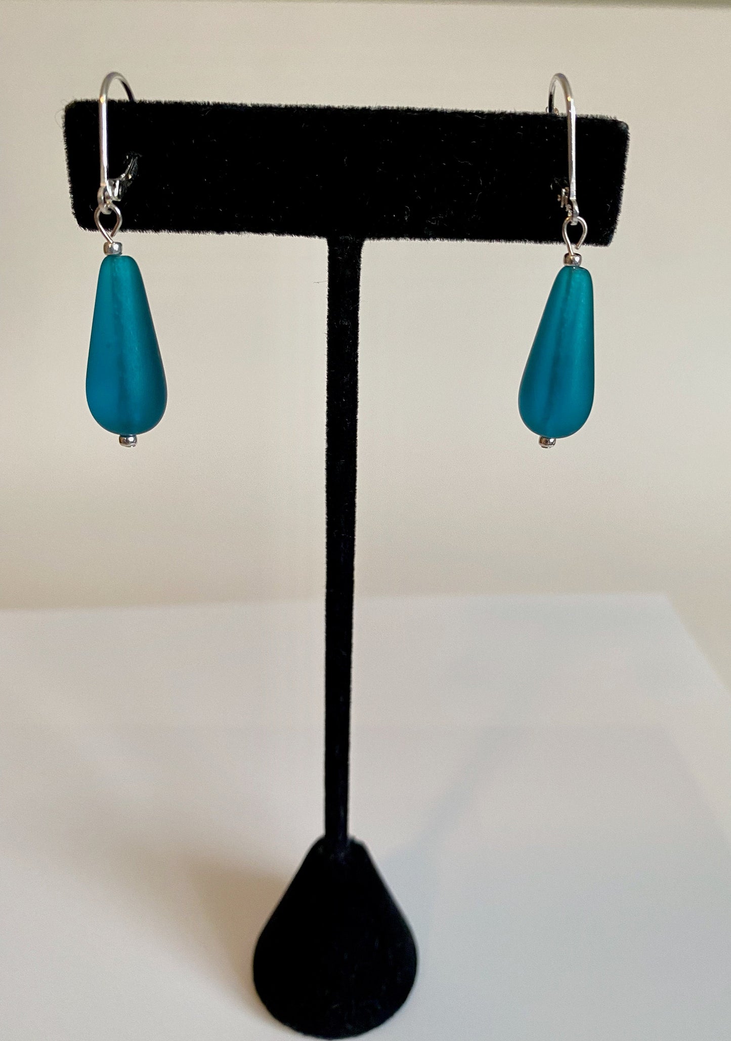 Soft sea glass type frosted teal color teardrop earrings. Fashioned with a quality sterling silver lever back clasp.