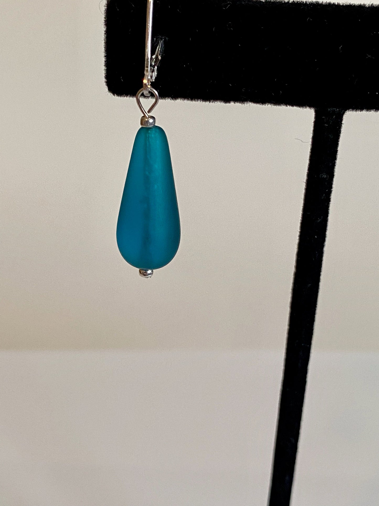 Soft sea glass type frosted teal color teardrop earrings. Fashioned with a quality sterling silver lever back clasp.
