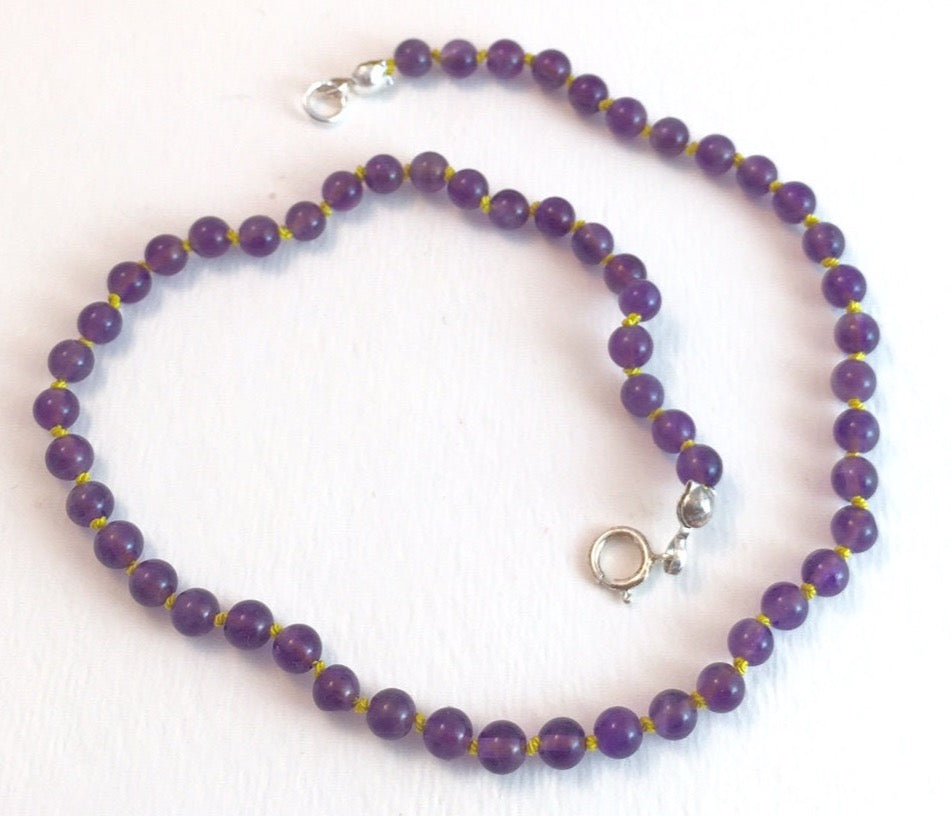 Children's treasured amethyst beaded necklace. Sweet as can be with contrasting yellow knotted thread. I measures 11 1/2 " long.